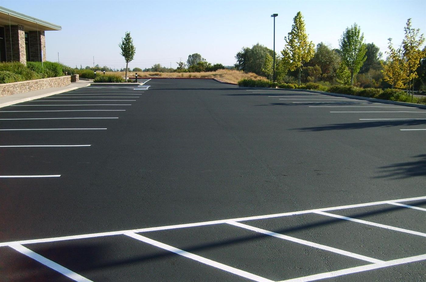 Sealed and striped parking lot with dry prairie grass beyond